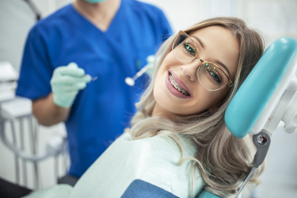 Beautiful woman with braces having dental treatment at dentist's office