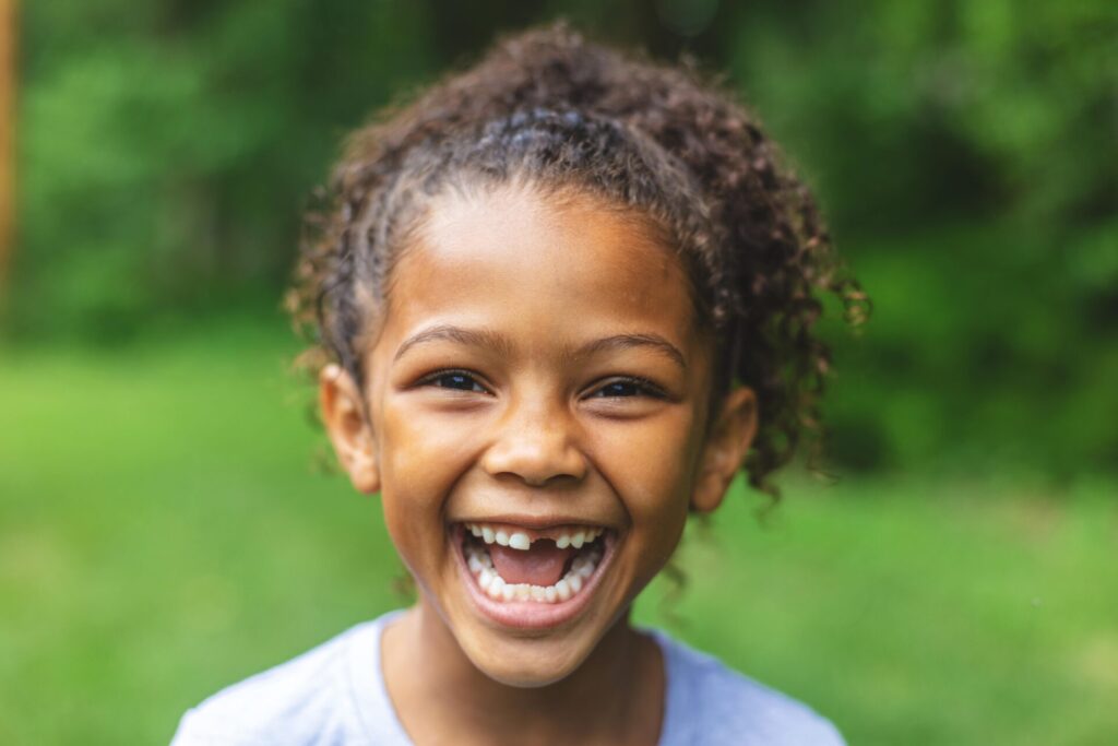 African American child smiling from ear to ear for a photo. She is showing her smile.